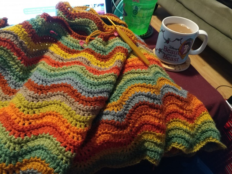 Photo of a crocheted blanket next to a mug of tea.