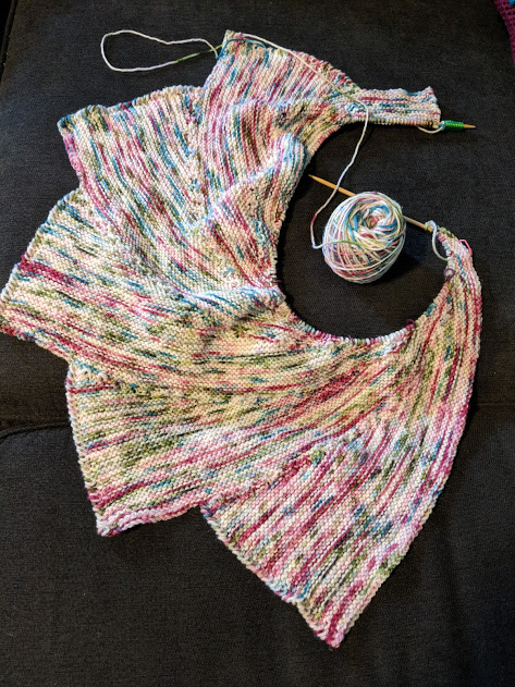 Shawl that somewhat resembles a dragon wing, in shades of cream, pink, blue, and green.