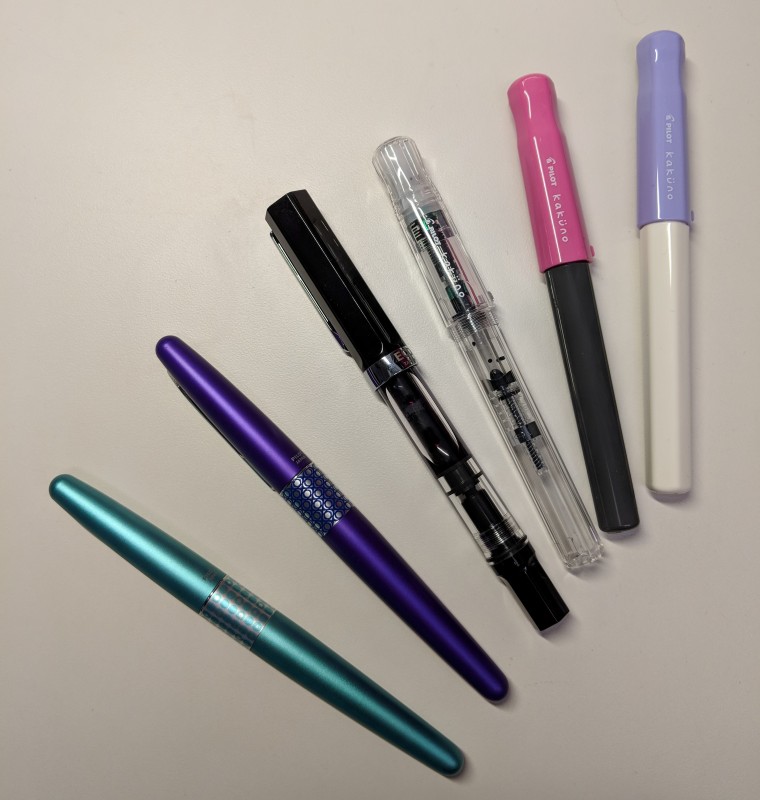 Photo of six fountain pens - two Pilot Metropolitans, a TWSBI Eco, and three Pilot Kakunos.