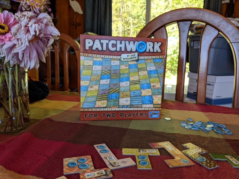 The box for the board game Patchwork, with game pieces surrounding the box.