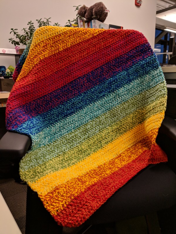 A rainbow blanket draped over a desk chair.