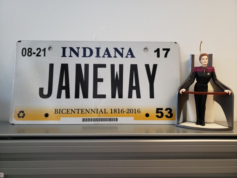 A June 2019 nerdy tidbit: Photo of a Captain Janeway Christmas ornament next to an Indiana vanity license plate that says JANEWAY.