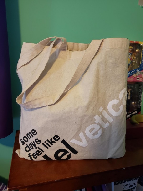 Image of a cream colored bag with the text 'Some days feel like Helvetica' on the front.