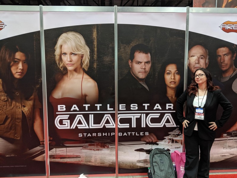 Me dressed as President Roslyn from Battlestar Galactica, in front of a wall with Battlestar Galactica characters on it.