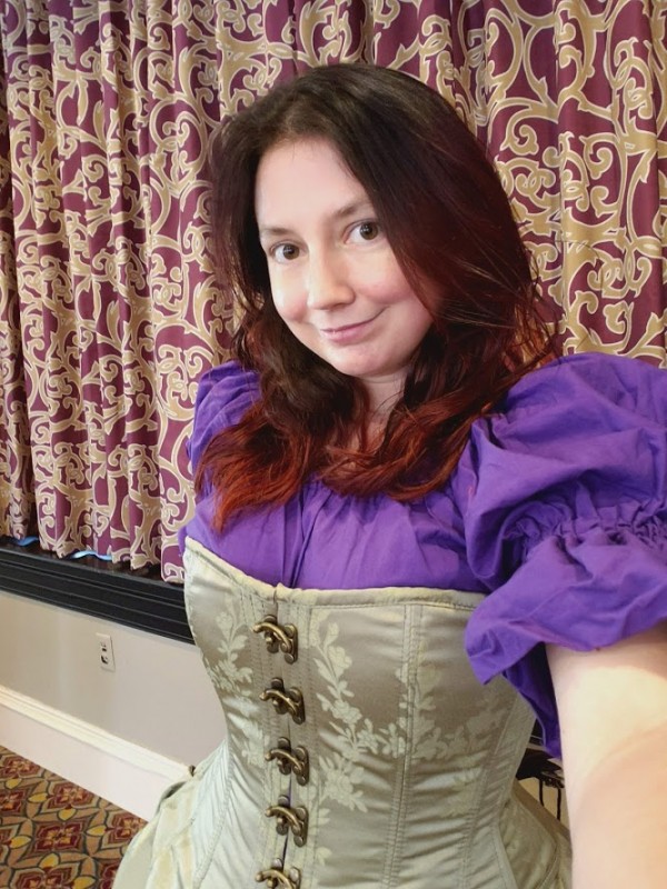 Me wearing a purple shirt with puffy sleeves and a green corset dress.