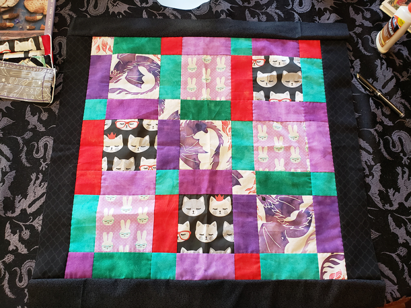 Quilt top featuring fabric with cats, dragons, and rabbits on it.