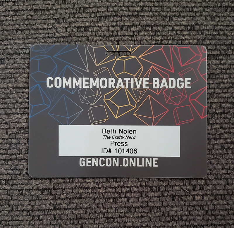 Photo of my Gen Con 2020 commemorative badge. A label with my name, the blog's name, and my Gen Con ID number printed on it has been applied to the back.