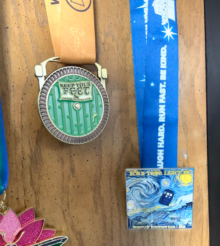 Two virtual race medals I earned recently - on the left is the one from the Keep Your Feet 5k, which looks like the door to a hobbit house, and the second is for the Roar Your Light 5k, which looks like Van Gogh's Starry Night painting with the TARDIS from Doctor Who flying through the sky.