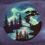 Photograph of a completed cross-stitch project, which features a stylized version of the northern lights.